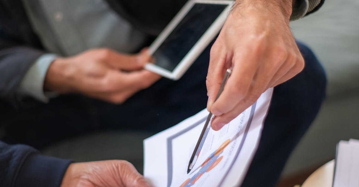 Two professionals in a business meeting discussing documents and a tablet.